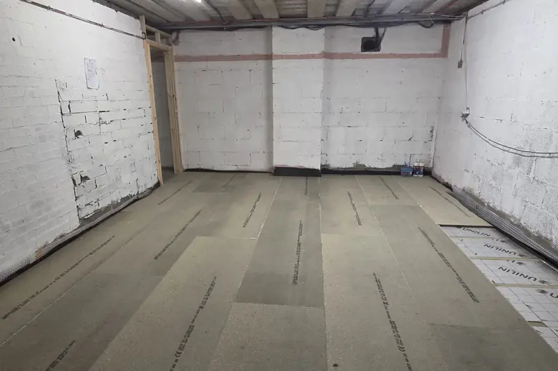 New floor boards laid over insulation in a white-painted block-walled room